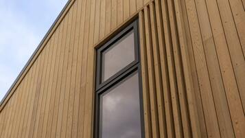 Een gebouw met een houten gevel en een groot raam.