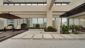 Un espacio exterior moderno con asientos, una fuente de agua y vistas de la ciudad.