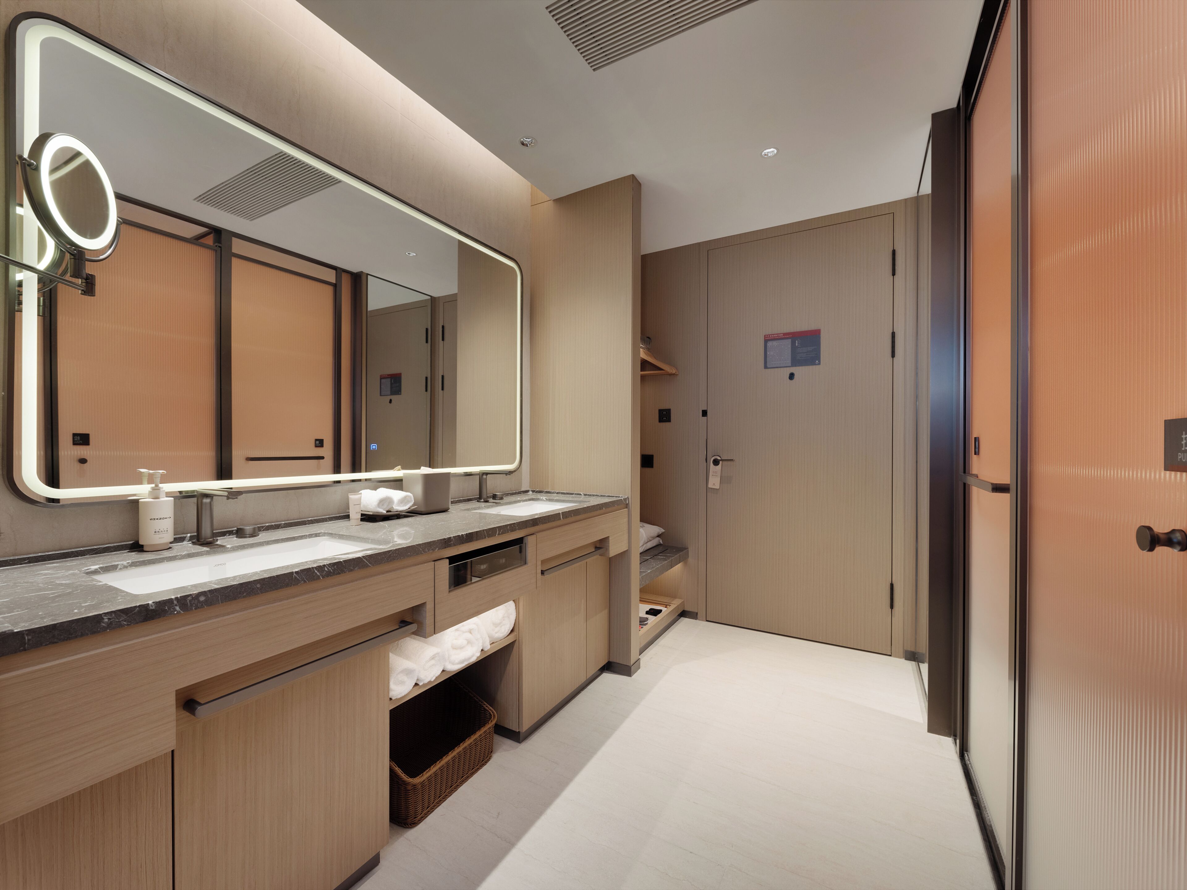 A modern bathroom with a large mirror, dual sinks, and a wooden vanity.