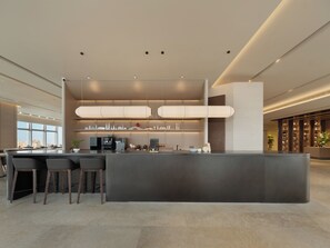Un área de bar moderna con un mostrador central, asientos y vistas a la ciudad.