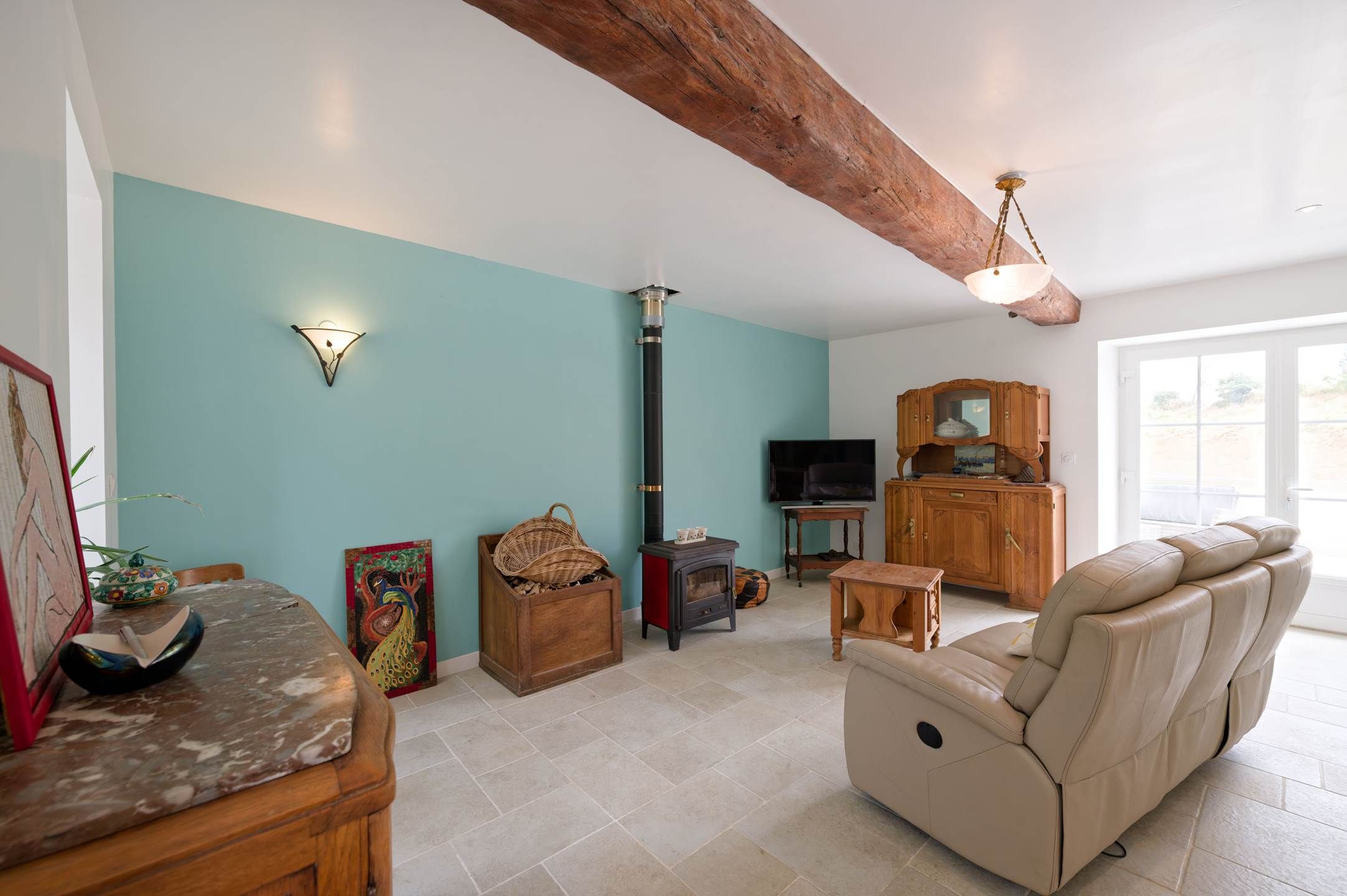 A spacious living room with a high ceiling, a fireplace, a comfortable sofa, and a television.