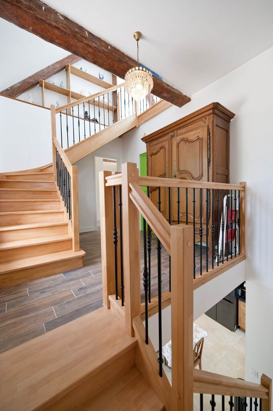 A wooden staircase with black balusters leading to a second-floor landing.
