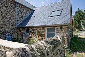 A stone building with a sloped roof, a small window, and a door.