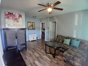 A living room with a ceiling fan, a sofa, a coffee table, and a cabinet. - Affordable 3-Bedroom Stay in Wailuku, Maui (Wailuku)
