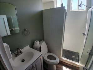 Casa de banho com sanita, lavatório e espelho.