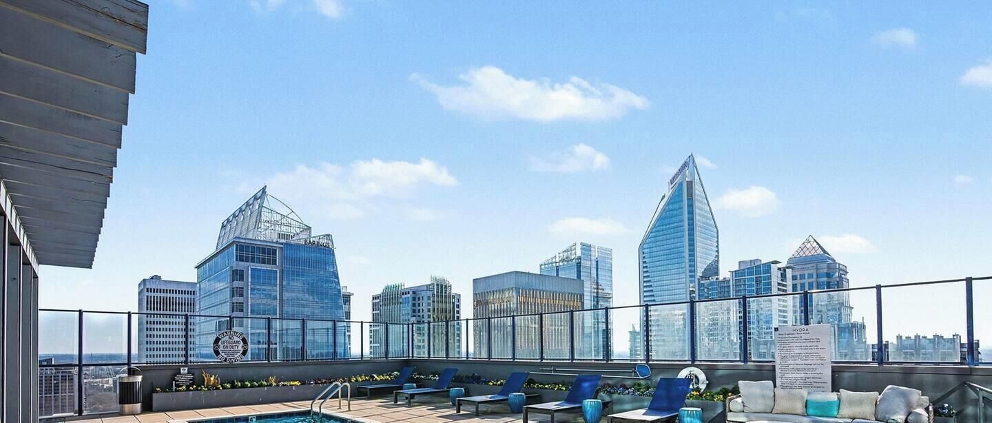A rooftop pool with a city skyline in the background, including a building with a distinctive shape.