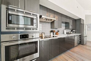 Een moderne keuken met roestvrijstalen apparatuur, een centraal eiland en een inbouwoven.