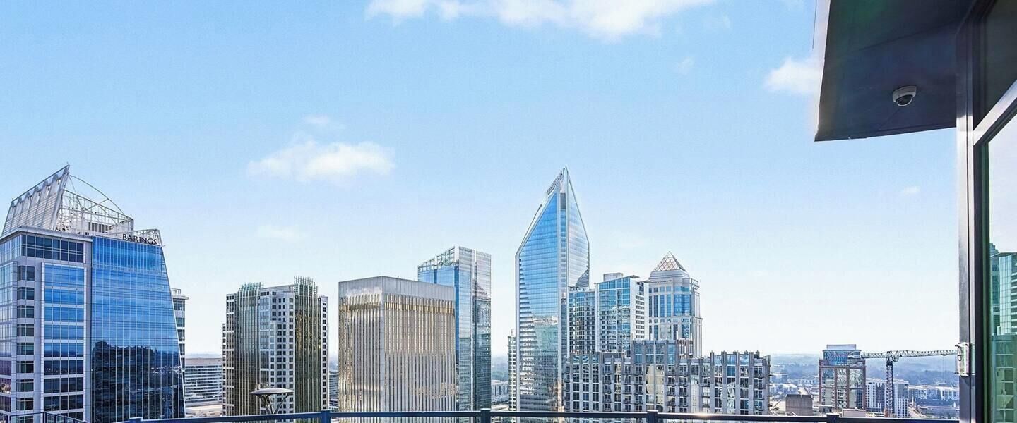 A city skyline with modern high-rise buildings, including a distinctive pointed skyscraper.