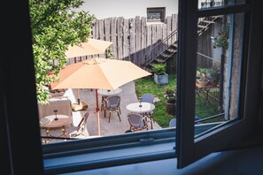 A view of a patio area with outdoor furniture and umbrellas, a wooden fence, and potted plants.