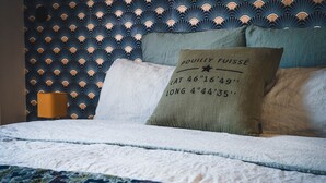 Uma cama com cabeceira estampada, um travesseiro com coordenadas e um abajur.