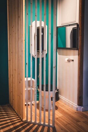 A bathroom with a wooden partition, a toilet, a sink, and a mirror on the wall.