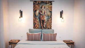 Een slaapkamer met een groot bed, twee nachtkastjes, een kunstwerk aan de muur en twee wandlampen.