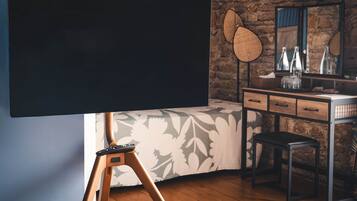 Een kamer met een bed, een dressoir, een spiegel en een groot zwart scherm.