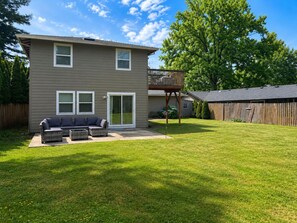 Ein zweigeschossiges Haus mit Terrasse, Deck und einem umzäunten Garten.