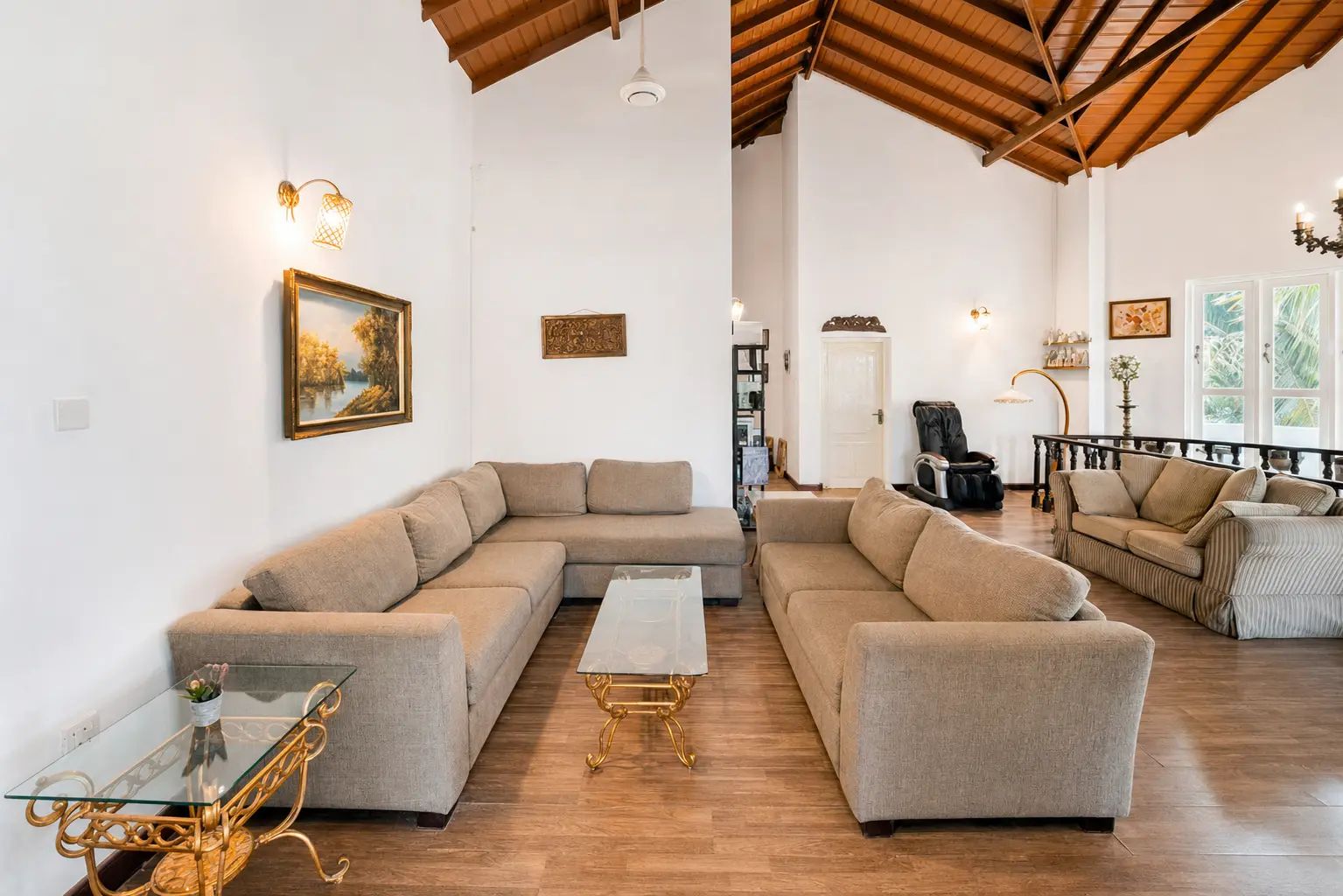 Amplia sala de estar con un sofá modular grande, una mesa de centro de vidrio y un sillón de cuero.