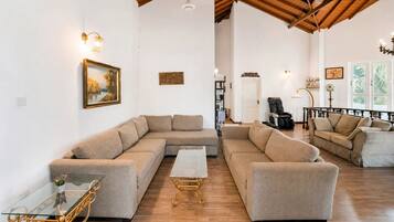 Amplia sala de estar con un sofá modular grande, una mesa de centro de vidrio y un sillón de cuero.