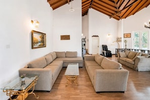 A spacious living room with a large sectional sofa, a glass coffee table, and a leather armchair. - Skyport Villa Negombo (Negombo)