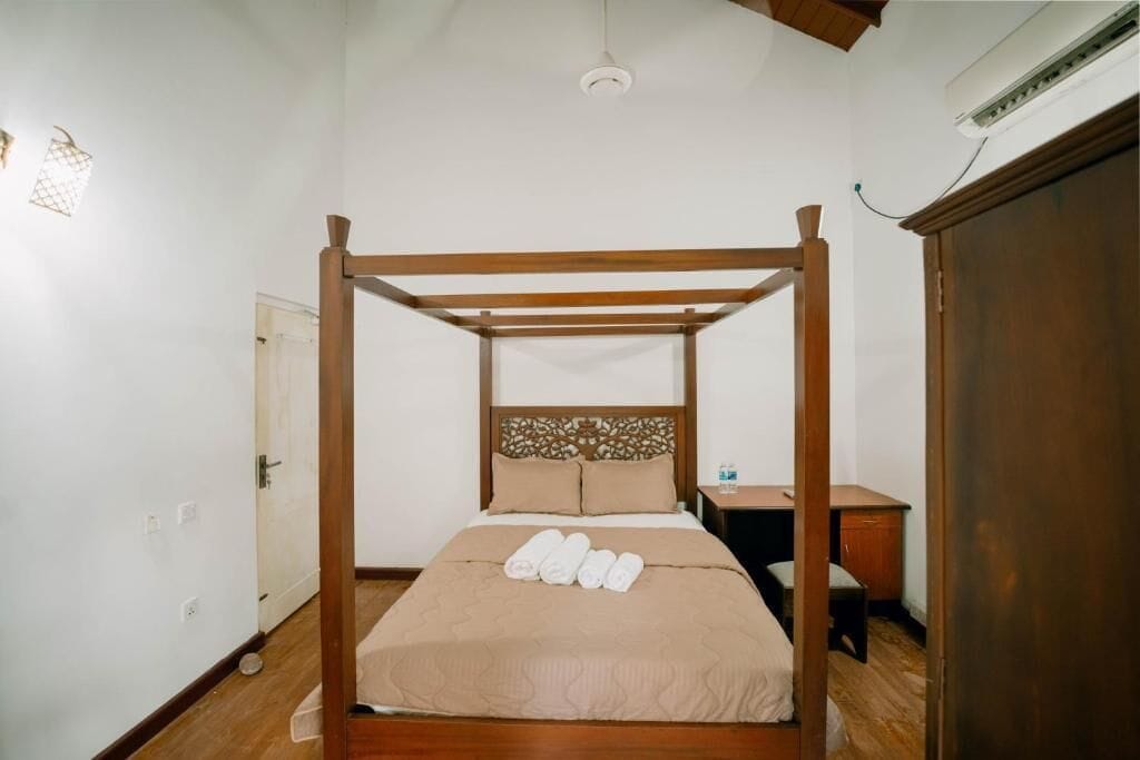Un dormitorio con cama con dosel, cabecera de madera, mesita de noche y armario.