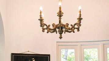 A chandelier with multiple candle-like lights, a framed maritime painting, and a white door with glass panels.