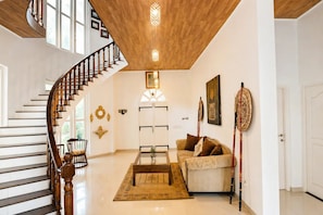A spacious living area with a wooden staircase, a sofa, a coffee table, and decorative items. - Skyport Villa Negombo (Negombo)