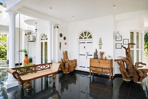 A spacious foyer with a polished black floor, a wooden bench, a rustic wooden cabinet, and a large tree trunk sculpture. - Skyport Villa Negombo (Negombo)