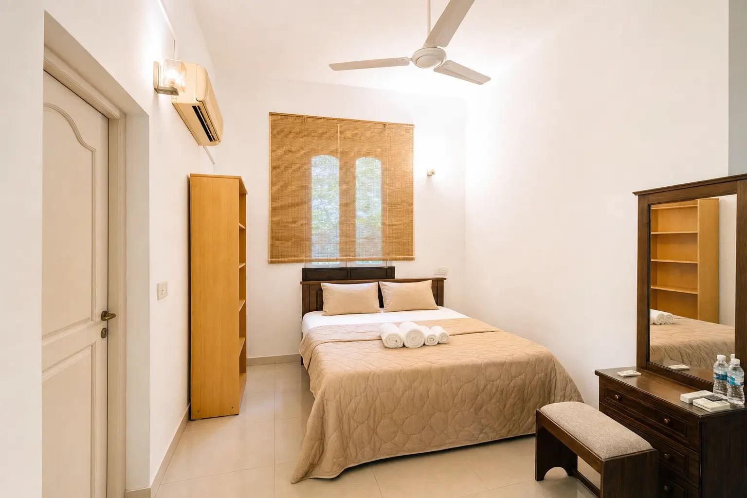 A bedroom with a bed, a wardrobe, a mirror, and a ceiling fan.