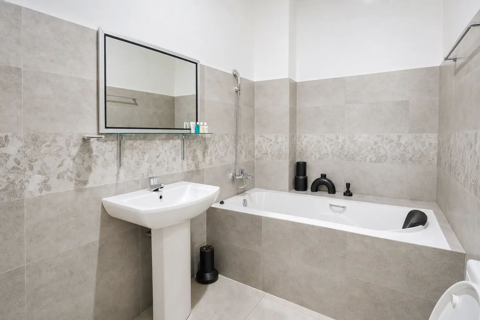 Un baño moderno con un lavamanos blanco, una bañera y un espejo.