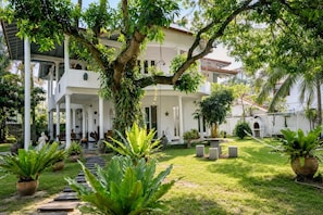 A two-story building with a covered patio, surrounded by lush greenery and a well-maintained lawn. - Skyport Villa Negombo (Negombo)