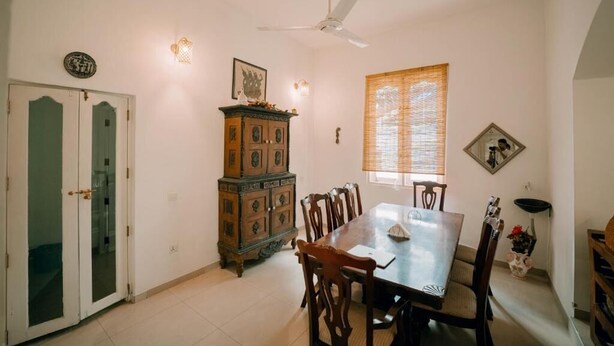 A dining area with a table and chairs, a ceiling fan, a cabinet, and a window with blinds. - Skyport Villa Negombo (Negombo)