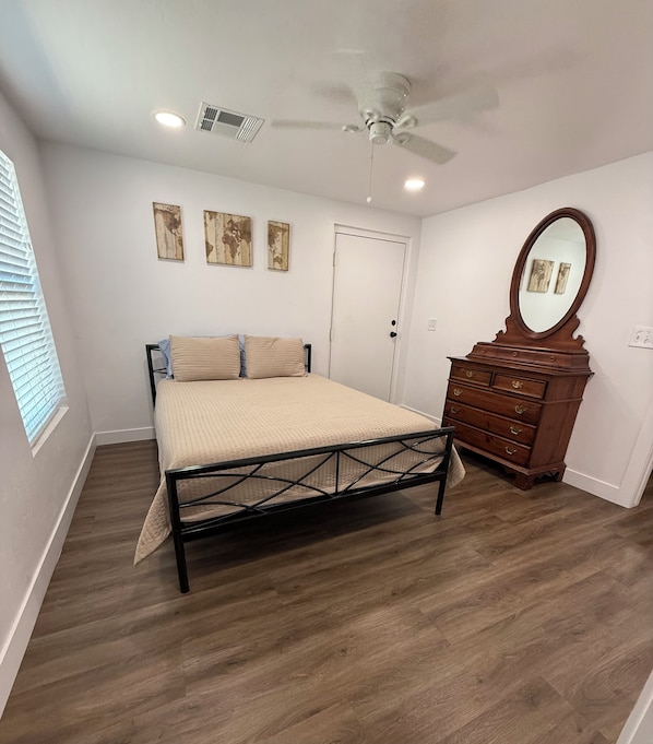 A bedroom with a bed, dresser, and ceiling fan.