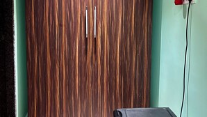 Ein Zimmer mit einem großen Kleiderschrank, einer Steckdose mit einem roten Stecker und einem schwarzen Gegenstand auf dem Boden.