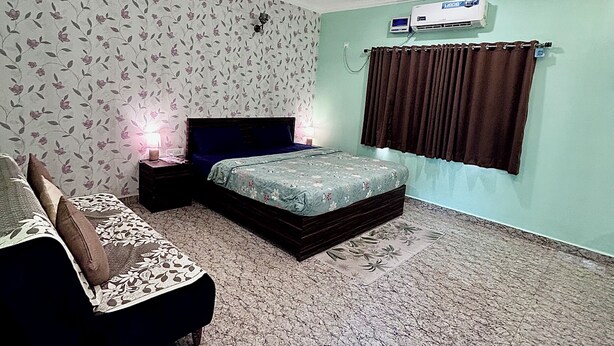 Ein Schlafzimmer mit einem Bett, einem Nachttisch, einem Deckenventilator und einer Klimaanlage.
