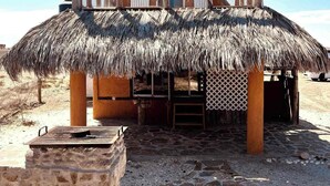 A thatched-roof structure with a stone base, possibly a beach hut or a small building. - "El Nirvana" Oceanfront Cabin: Surf & Desert (Punta Abreojos)