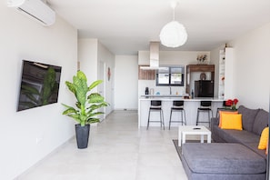 A modern kitchen with a central island, bar stools, and a dining area with a grey sofa and a small white table. - Nice View Apt 5 - 2-BR apartment with AC on spectacular Mahuma hill (Mahuma (Curacao-Middle))