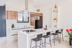 A modern kitchen with a central island, bar stools, a built-in oven, and a wine bottle. - Nice View Apt 5 - 2-BR apartment with AC on spectacular Mahuma hill (Mahuma (Curacao-Middle))