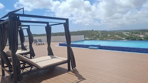 A rooftop pool area with a swing chair and lounge chairs. - Nice View Apt 5 - 2-BR apartment with AC on spectacular Mahuma hill (Mahuma (Curacao-Middle))