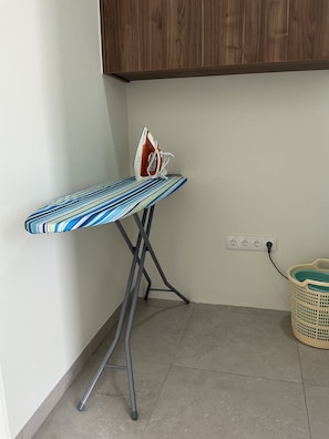 A corner room with a striped ironing board, an iron, a power outlet, and a laundry basket. - Nice View Apt 5 - 2-BR apartment with AC on spectacular Mahuma hill (Mahuma (Curacao-Middle))