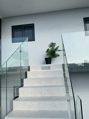 A modern staircase with glass railings and a potted plant. - Nice View Apt 5 - 2-BR apartment with AC on spectacular Mahuma hill (Mahuma (Curacao-Middle))