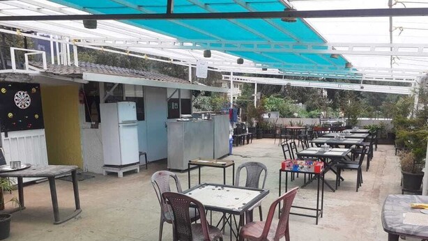 An outdoor patio area with tables and chairs, a covered seating area, and a small kitchen setup. - Eden Paradisee (Ootacamund)
