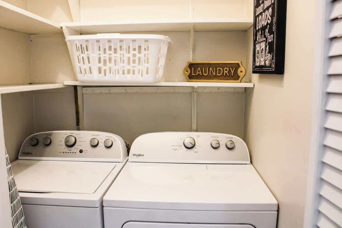 A laundry room with two Whirlpool washers, a white laundry basket, and a sign labeled 'LAUNDRY'.