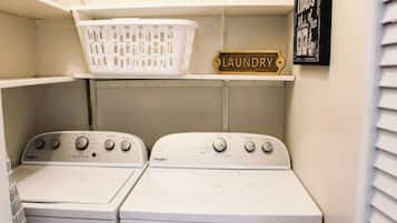 A laundry room with two Whirlpool washers, a white laundry basket, and a sign labeled 'LAUNDRY'.
