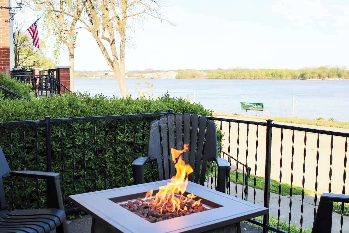 A patio with a fire feature, chairs, and a view of a body of water.