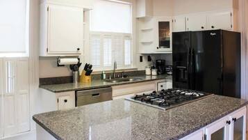 Una cocina moderna con encimeras de granito, un refrigerador negro y muebles blancos.