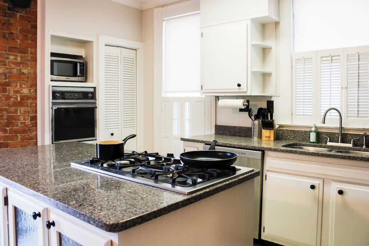 Una cucina con fornello a gas, forno a microonde, forno e mobili bianchi.