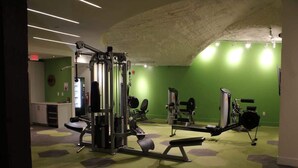 A gym with various exercise equipment, a green wall, and a ceiling with exposed concrete. - Walk to Bars & Dining — Free Parking & Gym (Louisville)