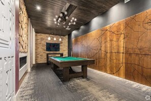 Une salle de billard équipée d’une table de billard, avec un mur en bois orné d’une carte et dotée d’un éclairage suspendu.