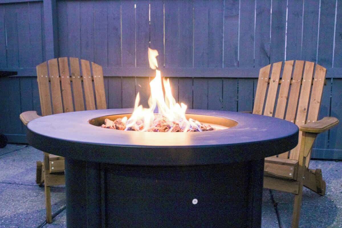 Un braciere rotondo all'aperto con due sedie di legno ai lati.