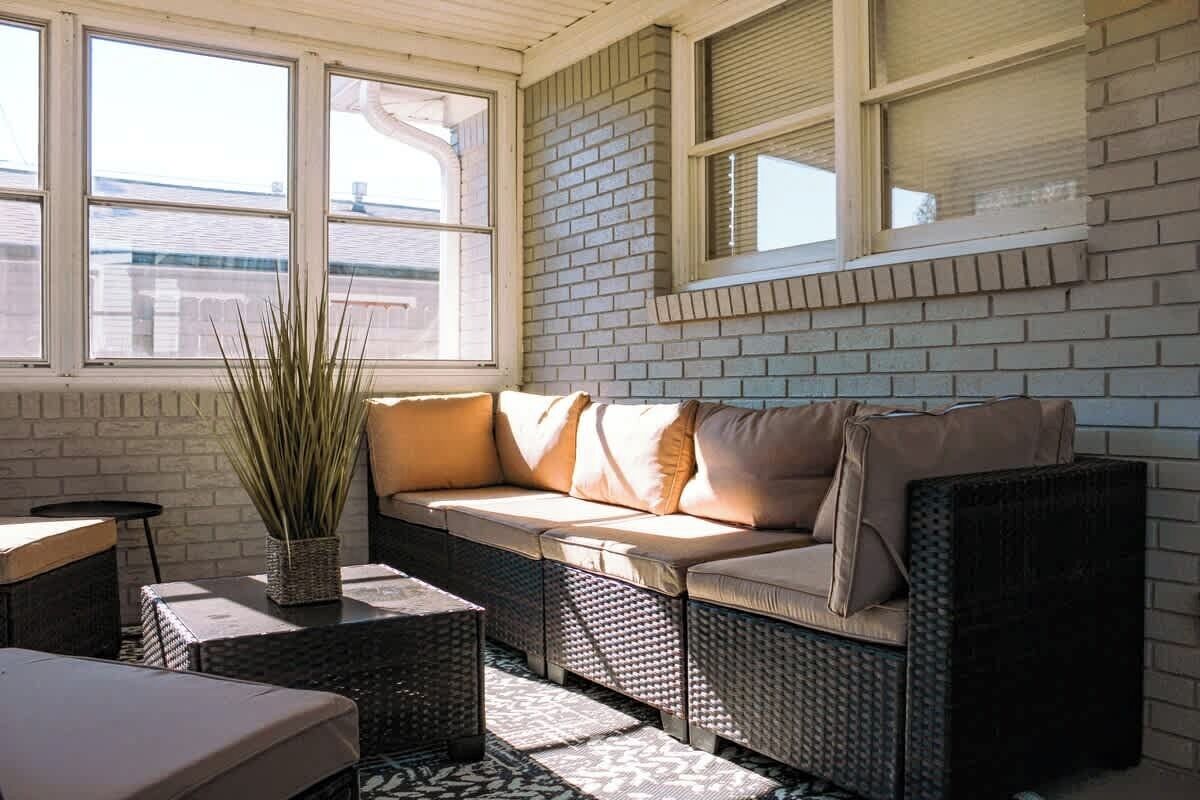 A sunlit room with a sofa, wicker furniture, and a potted plant.