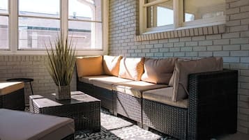 A sunlit room with a sofa, wicker furniture, and a potted plant.