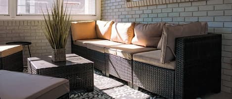 A sunlit room with a sofa, wicker furniture, and a potted plant.